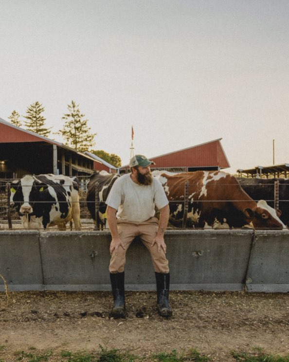 Click to shop the men's classic seamless. Image features a man sitting in front of a cow pasture.