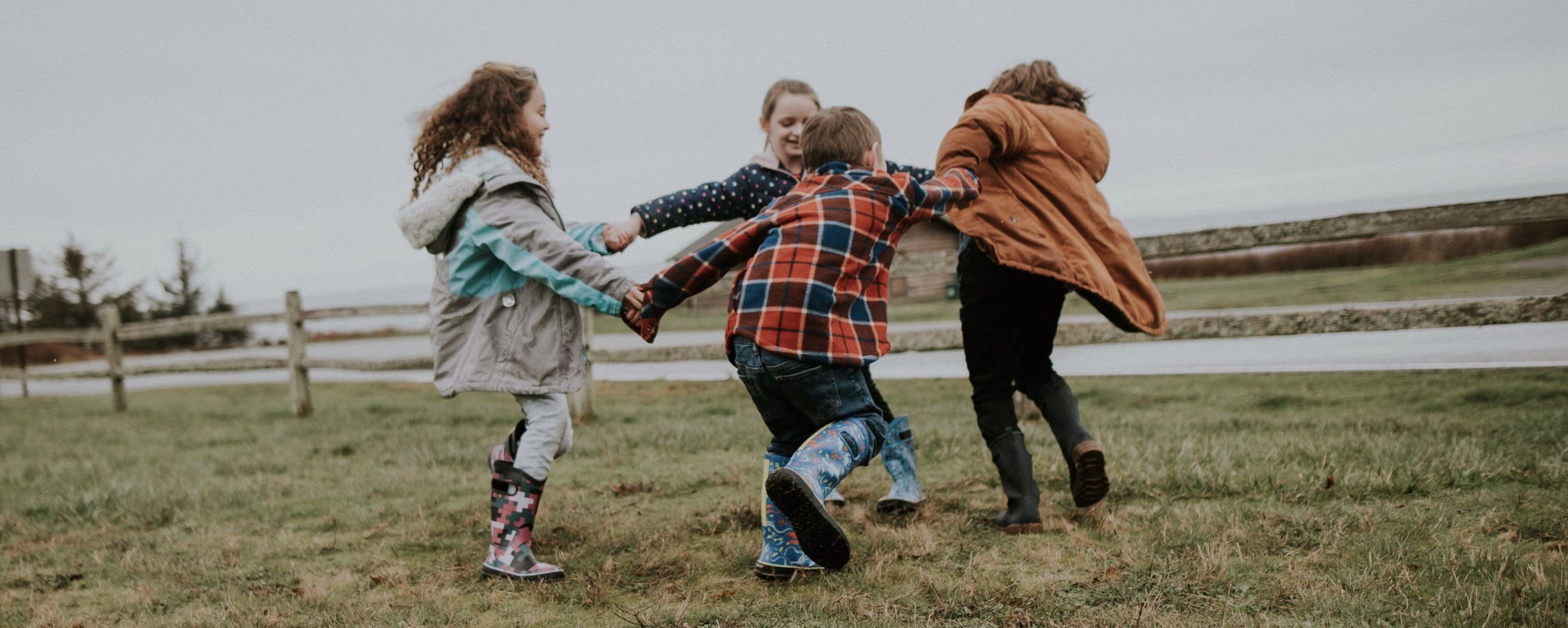 Shop our new Kids' Rainboot prints for Spring.  The image shown is a group of Kids holding hands and spinning around. Shop the variety of Kids' rainboot prints.