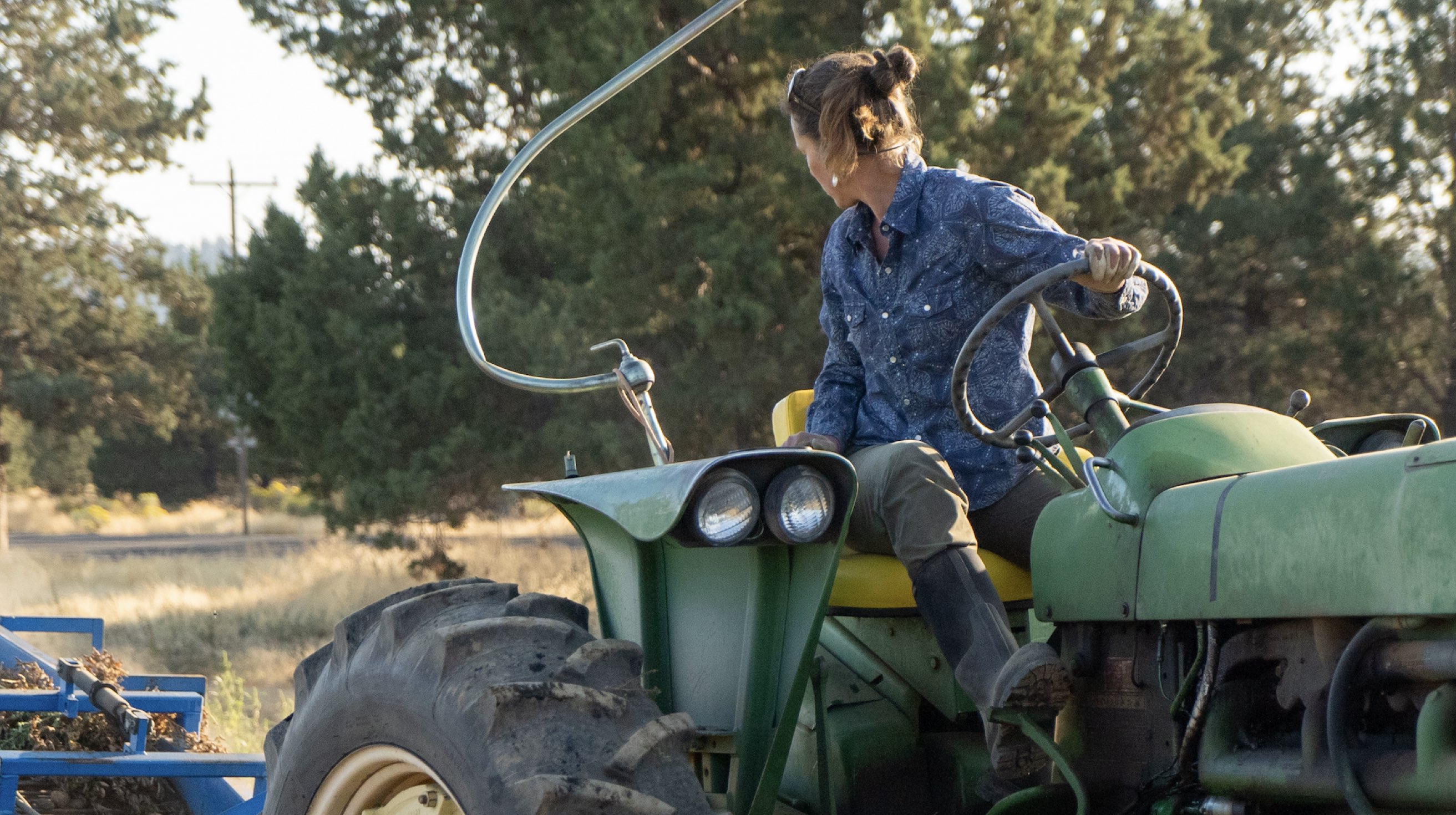 Click to shop women's work boots. Image features a woman on a tractor.