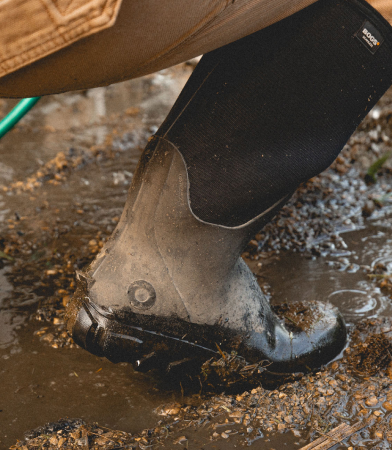 The closeup image shown is our Men's Classic Seamless boot tall in mud climbing up into a tractor.