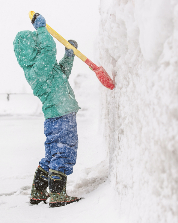 The image is a kid with a shovel, digging up the side of a snow mound. BOGS last pairs left sale. Shop now, before they are gone.