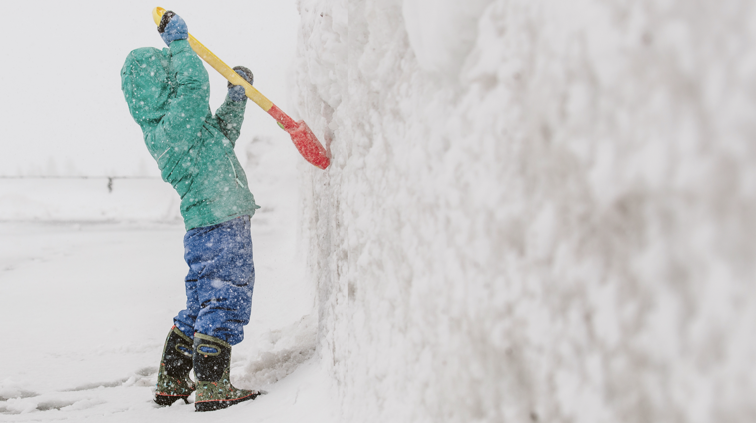 The image is a kid with a shovel, digging up the side of a snow mound. BOGS last pairs left sale. Shop now, before they are gone.