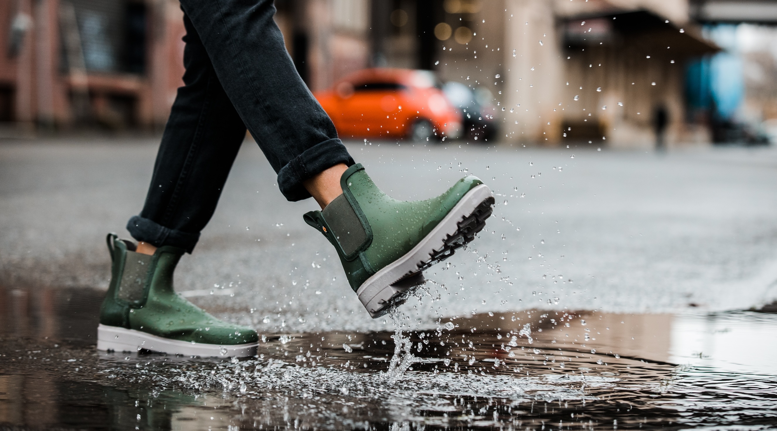 The image shown is a closeup of our women’s holly rainboot Chelsea in green splashing through a puddle. Shop now.