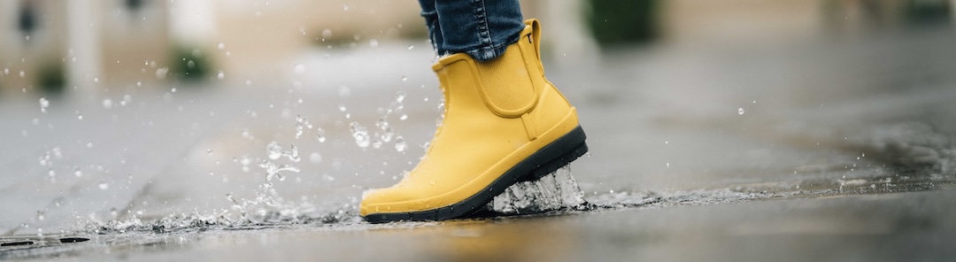 The image shown is our Women's Amanda II plush waterproof chelsea boot in mustard splashing in a puddle. Shop now.